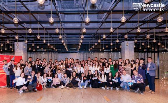 Group shot of China-based NUBS alumni in ballroom with hanging lights